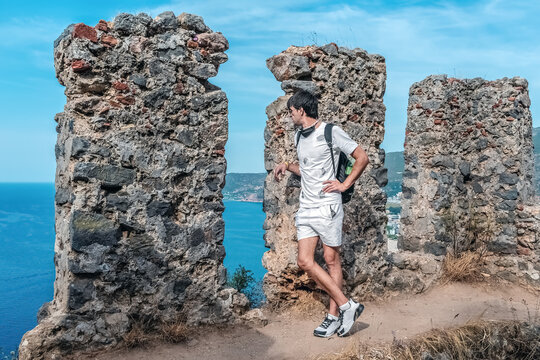 Traveler standing among ancient stone ruins at Alanya Castle, Turkey, with a panoramic view of the Mediterranean Sea in the background. Contrast between history and nature creates a serene atmosphere