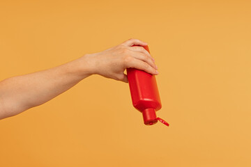 Hand squeezing a red bottle with an open flip-top lid