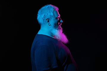 Profile of a bearded man looking away, deep in thought, with blue and pink neon lights highlighting his features.