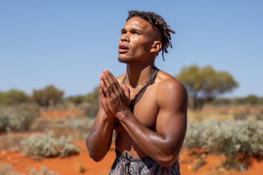 Indigenous man praying in the australian outback desert