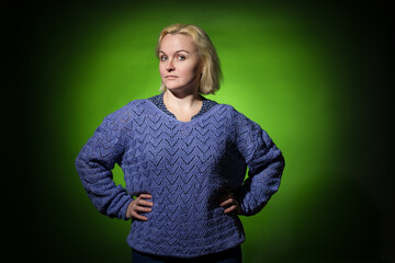 an adult woman in all non-knitted sweaters stands with her hands at her sides and looks at the camera