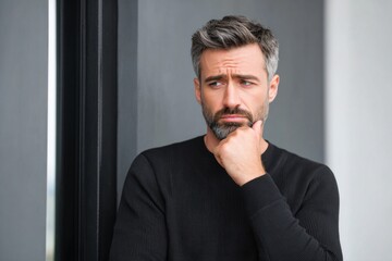 Pensive businessman leaning against wall and thinking about future projects