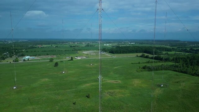 Drone footage capturing a towering guyed radio mast in the heart of a lush green rural field