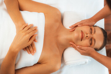 Fototapeta premium Panorama top view of woman enjoying relaxing anti-stress head massage and pampering facial beauty skin recreation leisure in dayspa modern light ambient at luxury resort or hotel spa salon. Quiescent