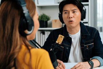 Smiling radio influencer host wearing headphone interviewing woman speaker sharing information to...