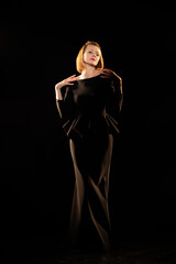 Woman in a black dress posing on a black background