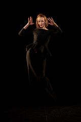 Fototapeta premium Woman in a black dress posing on a black background