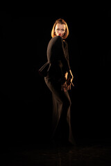 Fototapeta premium Woman in a black dress posing on a black background