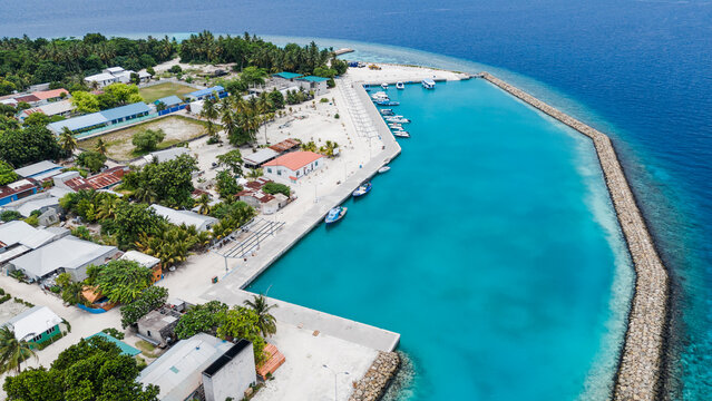 Aerial view of turquoise waters embrace the harbor, contrasting with the lush greenery of the island's interior, Kihaadhoo, Baa Atoll, Maldives.