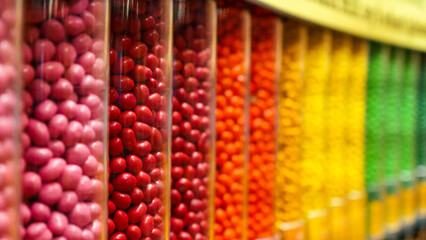 Colorful assortment of round candy drops in clear plastic containers arranged in a row.