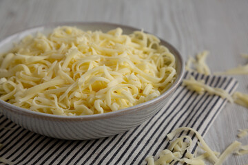 Organic Shredded Mozzarella Cheese in a Bowl, side view. Close-up.