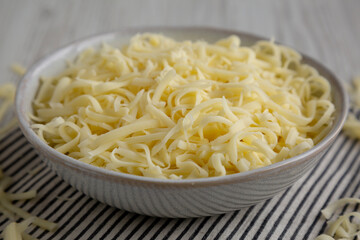 Organic Shredded Mozzarella Cheese in a Bowl, side view. Close-up.