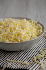 Organic Shredded Mozzarella Cheese in a Bowl, side view. Close-up.