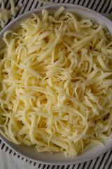 Organic Shredded Mozzarella Cheese in a Bowl, top view. Close-up.