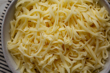 Organic Shredded Mozzarella Cheese in a Bowl, top view. Close-up.