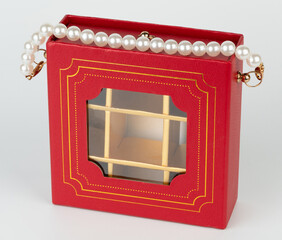 Elegant red box purse with pearl strap displaying intricate design details