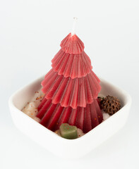 Colorful Christmas tree candle displayed in small white dish with decorative elements