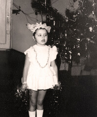 Vintage portrait of a girl dressed as a snowflake singing a song near a Christmas tree. Retro photo...
