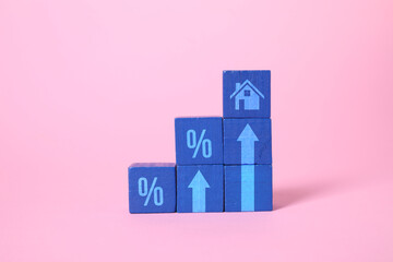 Increase in real estate value. Blue cubes with house icon, arrows and percent signs on pink...