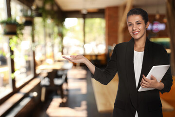Young hostess with tablet computer welcoming to restaurant
