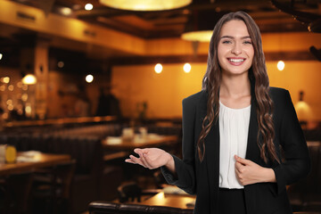 Young hostess in uniform welcoming to restaurant
