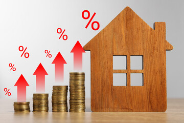 Increase in real estate value. House model and coins on table. Growing price represented by arrows...