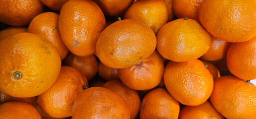 A pile of fresh, ripe oranges with shiny orange skin creates a vibrant, natural look. The fruits...