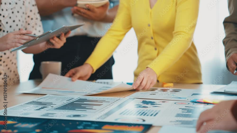 Poster a diverse group of business professionals engaged in a collaborative meeting, examining charts and s