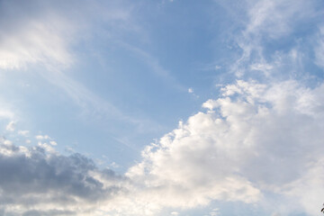 Soft white clouds scattered across a light blue summer sky