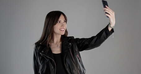 Happy young woman taking a selfie with her smartphone, smiling and looking at the screen