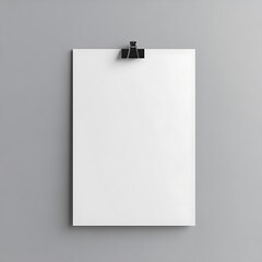 Simple white sheet of paper is clipped to a gray wall, providing space for a message or branding template.