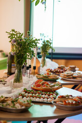 Rustic Chic Wedding or Celebration Appetizers Table with Wildflower Bouquets, White Candles, and Fresh Crostini Arrangements on Wooden Surface