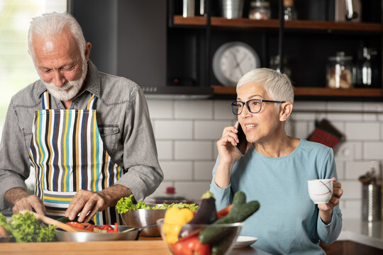 Smiling woman talking on phone while standing with man in kitchen