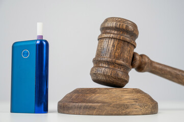 Judge's gavel and e-cigarette. Smoking ban. Tobacco heating systems. 