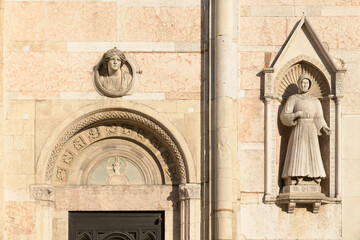 Side portal with lunette and statue of Alberto V d'Este in niche on the marble facade of Ferrara...