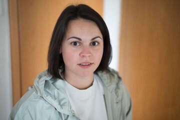 Surprised young woman in a jacket standing in an apartment doorway. Concept: unexpected moment, daily life, emotional reaction, indoor spontaneity.