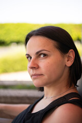 Young woman in a tank top sitting on a sunny balcony. Concept: summer relaxation, casual lifestyle, peaceful moments, outdoor comfort, slow living.