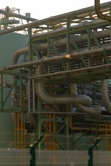A large industrial factory filled with numerous pipes and pipelines running through it efficiently,...