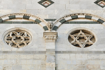 Twin rose windows on the facade of San Martino Cathedral in Lucca, Italy, featuring Romanesque...