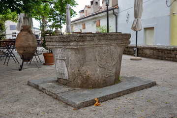 Ancient stone well with carved reliefs in Motovun, Croatia.