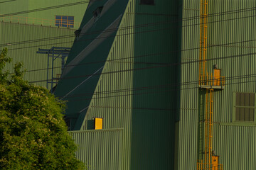There stands a large, vividly green building that features a striking yellow ladder mounted on its...