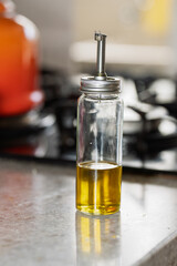 Close-up of a glass olive oil dispenser with metal spout and lid, placed on a polished kitchen...