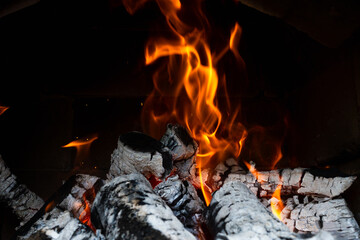 Bright tongues of flame and burning logs in a fireplace, close-up. A cozy atmosphere of warmth and...