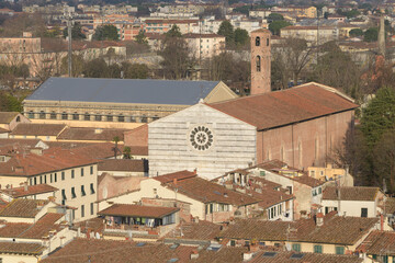 Facade and bell tower of San Francesco Church in Lucca, Tuscany, Italy, seen above red-tiled...