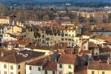 View over Piazza dell'Anfiteatro and historic red rooftops of Lucca, Tuscany, Italy, with the Apennine Mountains in the background.