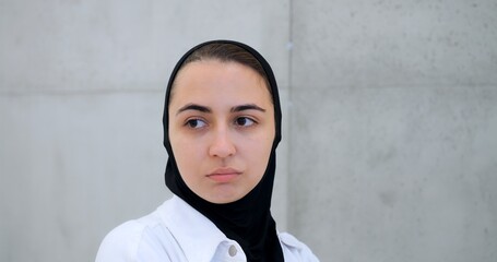 Muslim woman in hijab displaying varied facial expressions from contemplative to intense, standing...