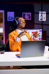 Cheerful freelancer with wireless headphones enthusiastic about working from home office, dancing...