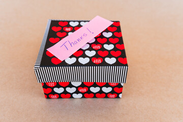 Thank you note that says thank you handwritten with blue pen with a background of a gift box with...