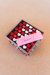 Thank you note that says thank you handwritten with blue pen with a background of a gift box with...