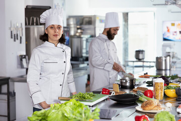 In a bustling restaurant kitchen, chef in uniform cooking delicious cuisine by preparing...
